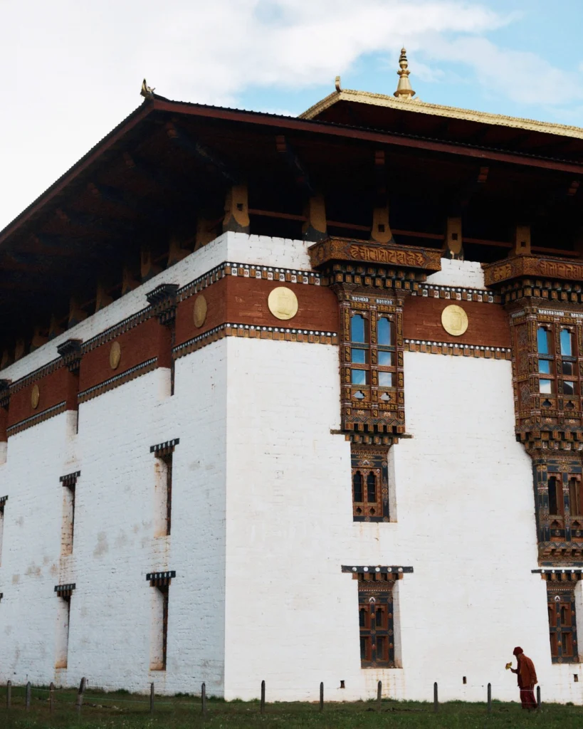 Whitewashed walls and carved wooden windows of a Bhutanese dzong under a blue sky