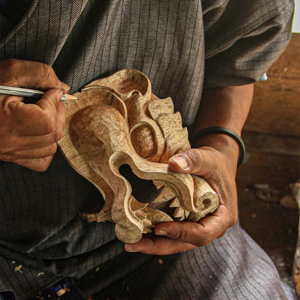 A craftsman carving a wooden mask by hand