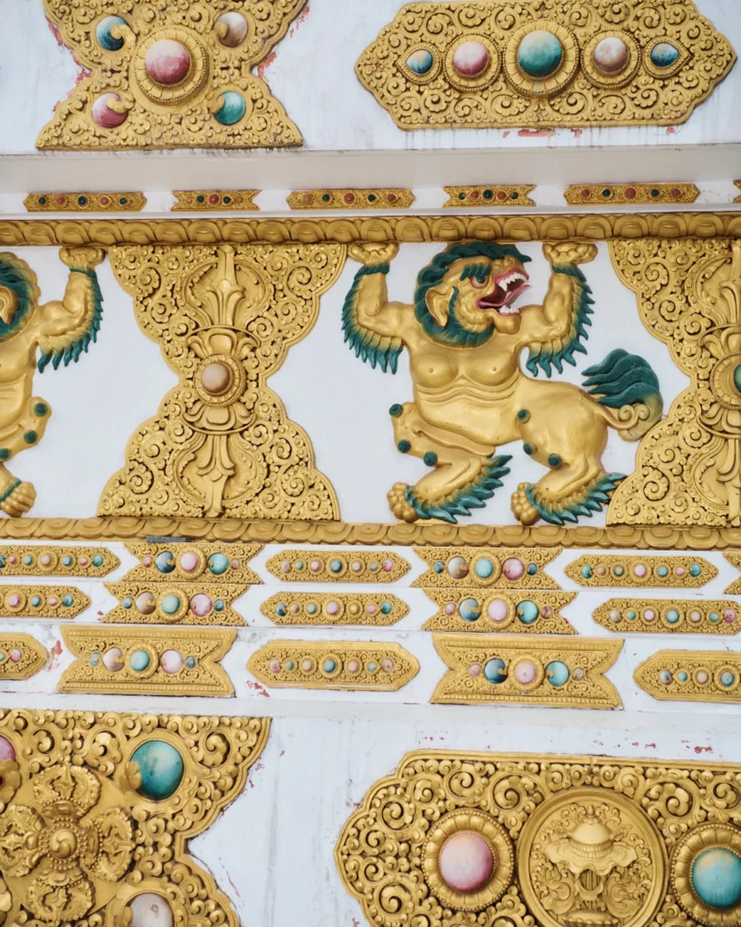 Gilded carvings of a snow lion and jewels on a temple wall