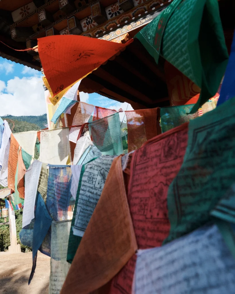 Colourful prayer flags hanging beneath the carved eaves of a building