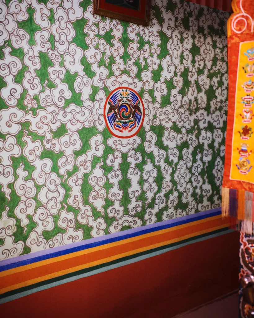 Painted temple wall with green cloud motifs and a colourful emblem